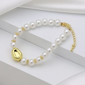 Detailed macro of pearl bracelet with golden irregular bead and gear accents on white silk