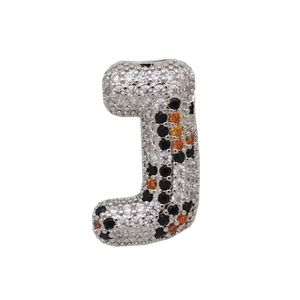 Macro detail of J-shaped letter pendant with silver metal and tricolor zircon inlay