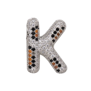 Macro shot of silver letter K balloon pendant with orange and black zircon pattern