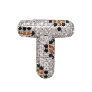 Macro detail of letter T pendant with silver metal and multi-color zircon pavé setting