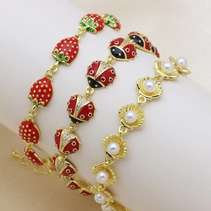 Three-piece gold bracelet set with strawberry, ladybug, and pearl shell charms