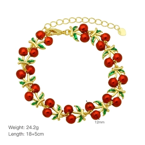 Close-up of golden cherry bracelet with red enamel fruit charms and size dimensions