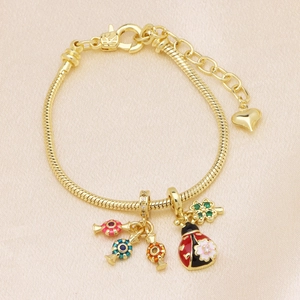 Gold snake chain charm bracelet with ladybug and clover pendants on silk background