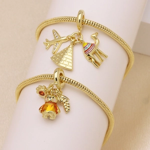 Detailed view of gold snake chain bracelets with pyramid, camel, and airplane charms