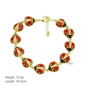 Close-up of ladybug charm bracelet with red enamel and crystals on adjustable gold chain
