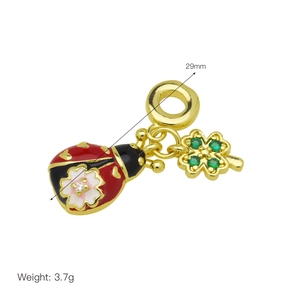 Macro shot of gold ladybug and green four-leaf clover pendant with enamel details