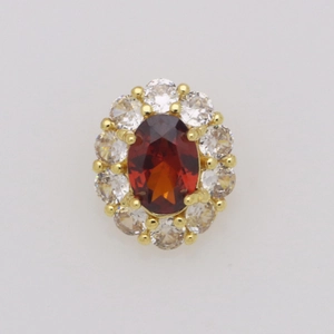 Dettaglio macro del ciondolo ovale con pietra rossa, halo di diamanti e placcatura oro 18k