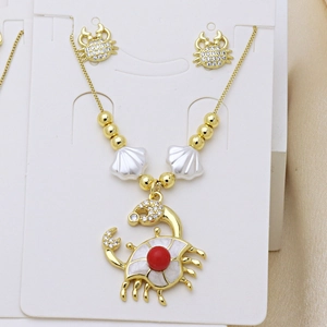 Dettaglio di un set di gioielli a forma di granchio dorato con perline rosse e conchiglia