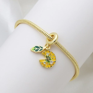 Golden snake chain bracelet with lemon slice charm and green leaf pendant