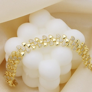 Elegante pulsera dorada con dijes de corazón pulidos e incrustaciones de circonitas