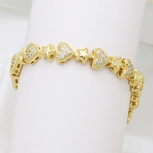 Detalle de pulsera dorada con corazones de circonitas y estrellas de metal pulido