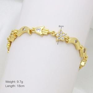Detalle de pulsera de oro con mano de Fátima, luna y colgantes con piedras de circón