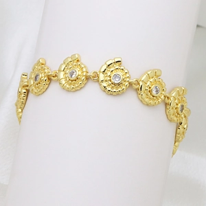Macro view of gold-plated bracelet featuring spiral nautilus links with cubic zirconia