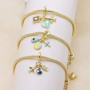 Three gold charm bracelets with travel-themed pendants on white display stands