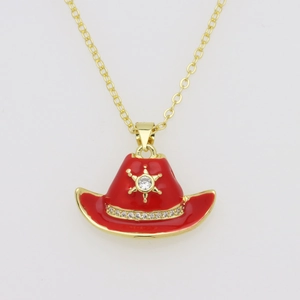 Detalle macro de un colgante de sombrero de vaquero en esmalte rojo bañado en oro con circonitas