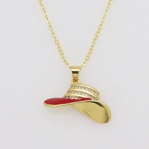 Detalle de un colgante de sombrero vaquero dorado con esmalte rojo y diamantes de imitación