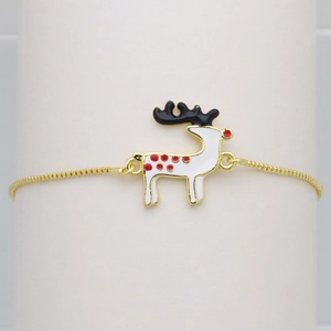 Macro shot of reindeer charm with red spots on gold snake chain adjustable bracelet