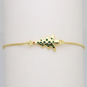 Macro view of golden snake chain bracelet with a green enamel Christmas tree charm