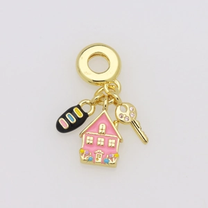 Detail of golden charm ring featuring pink house, black spotted oval and key pendant