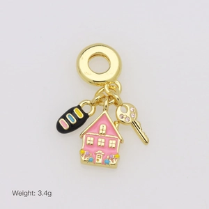 Detail of gold charms featuring pink enamel house, key, and striped bead on a ring