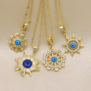 Golden evil eye pendant necklaces with blue zircon accents on champagne silk background