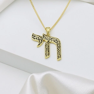 Gold Chai pendant necklace with black enamel detail on minimalist white geometric steps