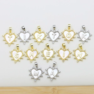 Macro detail of heart-shaped shell pendants with pavé zircon letters in gold and silver