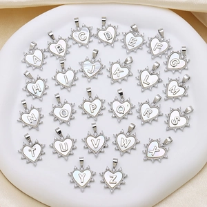 Macro shot of 26 heart-shaped alphabet charms featuring white shell inlay and zircon border