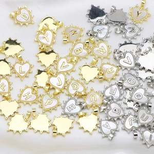 Macro detail of heart-shaped alphabet pendants with mother-of-pearl and cubic zirconia