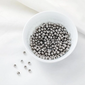 Macro shot of polished silver metal beads in a white bowl for DIY jewelry making