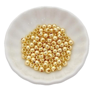 Polished 14K/18K gold filled round beads for DIY jewelry making in a white ceramic dish