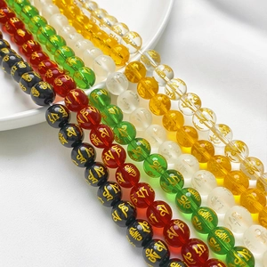 Macro shot of colorful glass beads with golden Buddhist mantra engraving for DIY jewelry