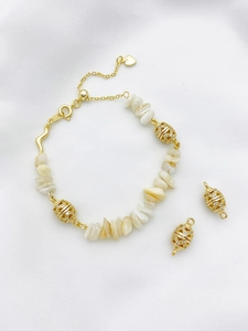 Detailed macro of 14K gold plated bracelet showing zircon hollow beads and shell pieces