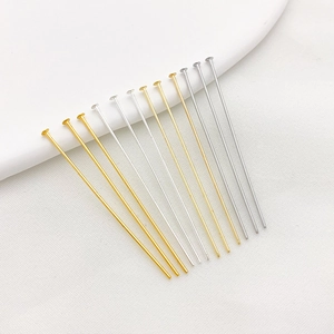 Close-up of gold and silver plated T-pins for DIY jewelry making on white ceramic tray