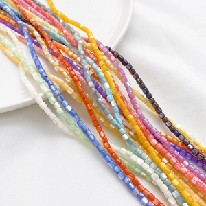 Bunte quadratische Muschelperlen für DIY-Schmuckherstellung auf weißem Keramikteller