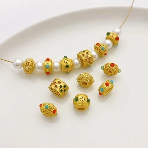 Detalle de cuentas caladas en oro mate de 18K con piedras de colores y perlas