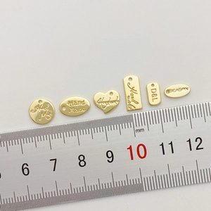 Vista macro de varios dijes DIY chapados en oro con escala de tamaño sobre fondo blanco