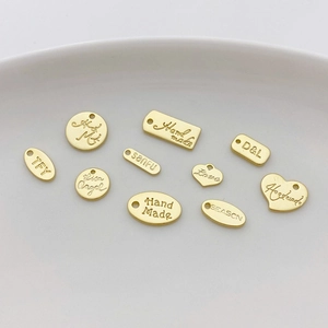 Vista de detalle de dijes de corazón y redondos bañados en oro 14K para joyería artesanal