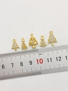 Nahaufnahme vergoldeter Weihnachtsbaum-Anhänger mit Zirkonia und Maßen auf einem Lineal