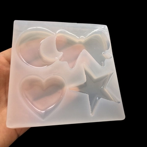 Hand holding translucent silicone mold with moon, bow, heart and star shapes