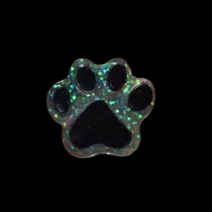 Macro detail of paw-shaped resin pendant with green and purple laser glitters