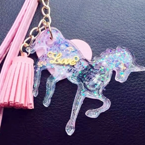 Macro view of purple resin unicorn keychain with glitter, Love charm and pink tassel