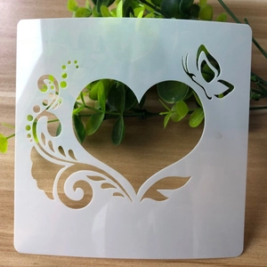 Detail of heart and butterfly hollow stencil on a rustic wooden background with greenery
