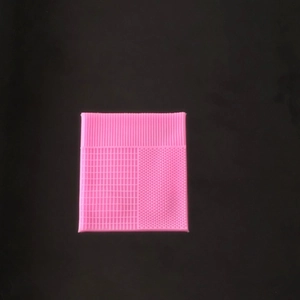 Pink silicone texture mat with three cleaning patterns for makeup brushes on black background