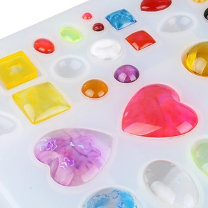 Macro detail of various geometric resin heart pendants and a silicone mold for DIY crafts