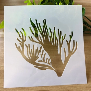 White translucent square stencil with coral pattern on wooden table for DIY journal art