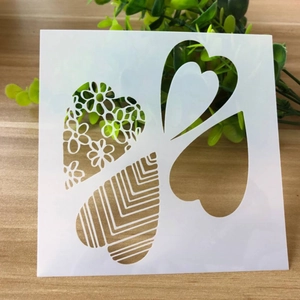 Detail of white square plastic stencil with various heart patterns and floral cutouts