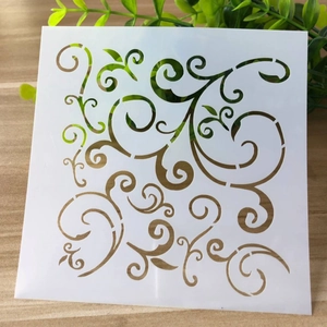 Detail view of square white stencil with floral vine patterns on a wooden desk