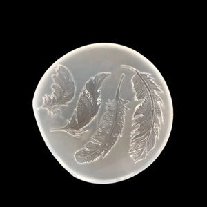 Macro detail of translucent silicone mold with four delicate feather patterns for DIY crafts