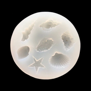 Macro shot of circular silicone mold featuring starfish and seashell cavities for DIY resin art